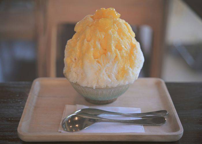 A hearty serving of kakigori shaved ice, with a mango syrup poured on top.